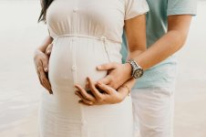 A pregnant woman and a man gently hold her belly